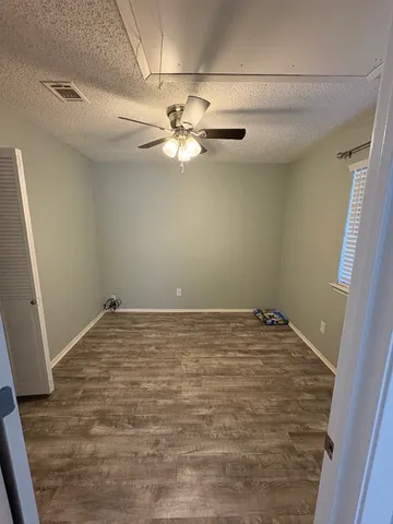 a view of a room with a ceiling fan and hardwood floor