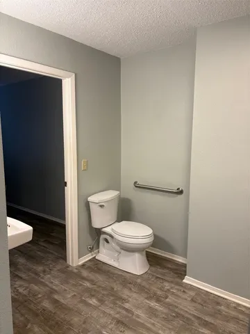 a toilet sitting in a bathroom next to a wooden cabinet