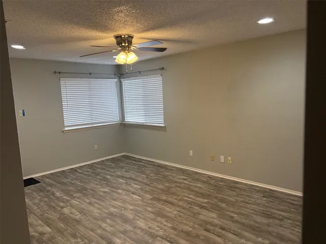 an empty room with a window and a ceiling fan