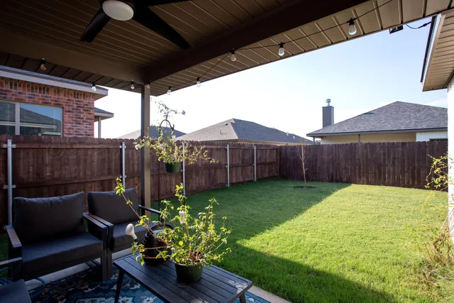 a view of a backyard with chairs potted plants and wooden fence
