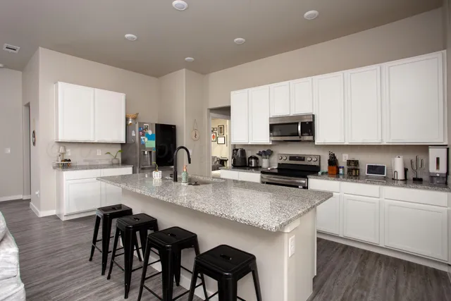 a kitchen with granite countertop white cabinets and stainless steel appliances