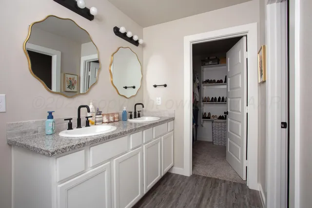 a bathroom with a granite countertop double vanity sink and a mirror