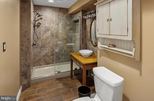 a bathroom with a sink a toilet a mirror and shower