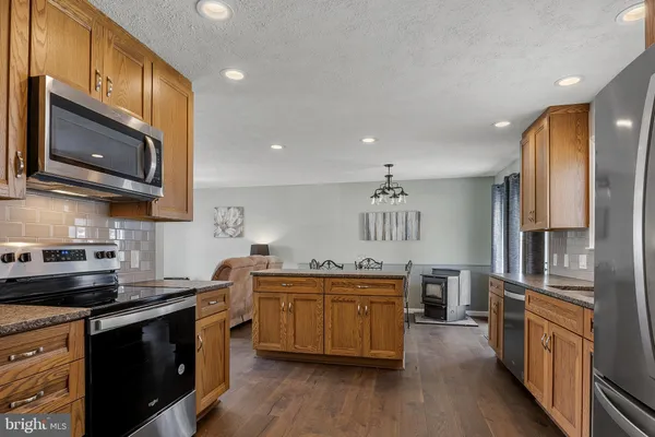 a kitchen with stainless steel appliances granite countertop a sink a stove top oven and wooden floors