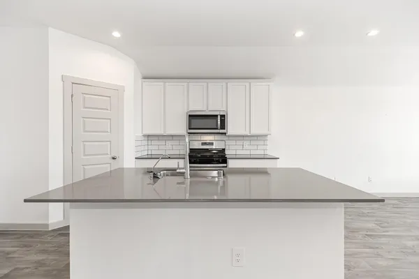 a kitchen with kitchen island a sink a stove a microwave and wooden cabinets