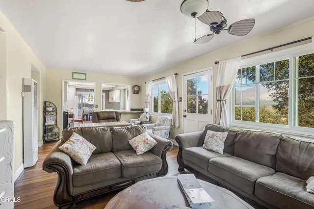 a living room with furniture large window and wooden floor