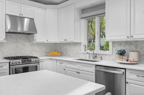 a kitchen with stainless steel appliances a white cabinets and a window