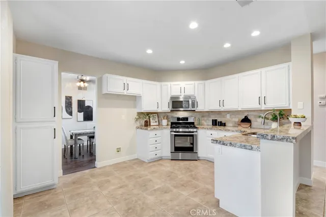 a kitchen with kitchen island granite countertop a stove top oven a refrigerator a dining table and chairs with wooden floor