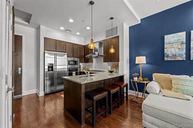 a kitchen with kitchen island a stove a refrigerator a sink and a dining table with wooden floor