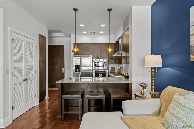 a kitchen with kitchen island stainless steel appliances a dining table chairs sink and wooden floor