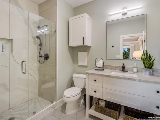 a bathroom with a granite countertop sink a toilet and shower