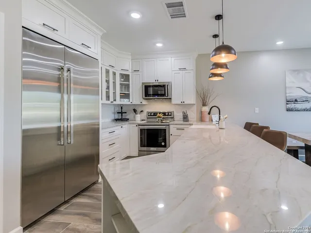 a kitchen with kitchen island a counter top a refrigerator and a sink