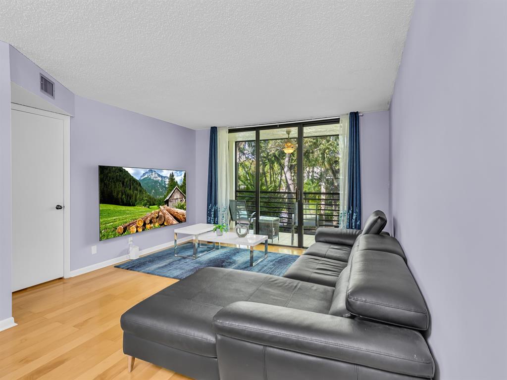 7579 Northwest 79th Avenue, Unit 204 Tamarac, FL 33321 - Photo 12 of 45 a living room with furniture and a flat screen tv