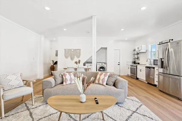 a living room with furniture kitchen view and a wooden floor