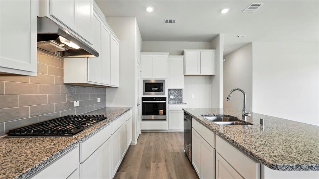 4191 Waldron Trail Forney, TX 75126 - Photo 2 of 20 Kitchen featuring white cabinetry, granite countertops, wood-finish flooring, stainless steel appliances, and a subway tile backsplash