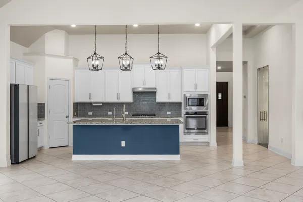 a large kitchen with stainless steel appliances granite countertop a sink a stove a refrigerator and a cabinets