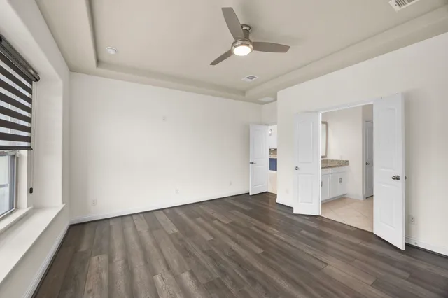 an empty room with wooden floor and windows