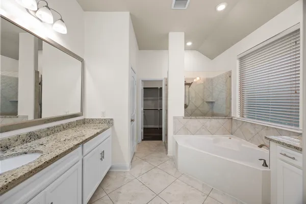 a spacious bathroom with a granite countertop tub sink and mirror