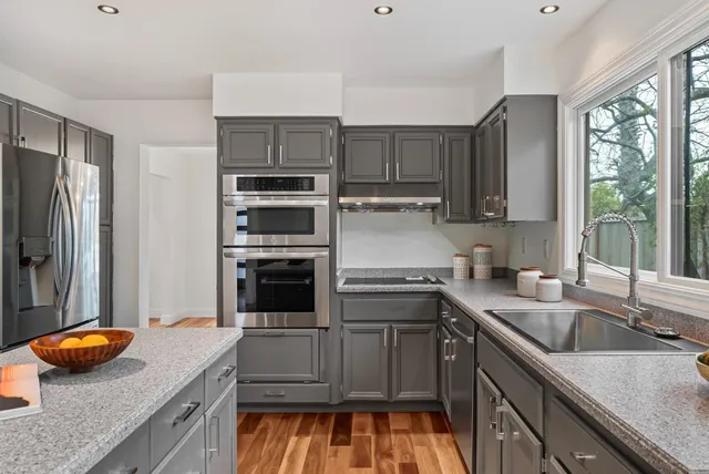 a kitchen with stainless steel appliances granite countertop a sink and a refrigerator