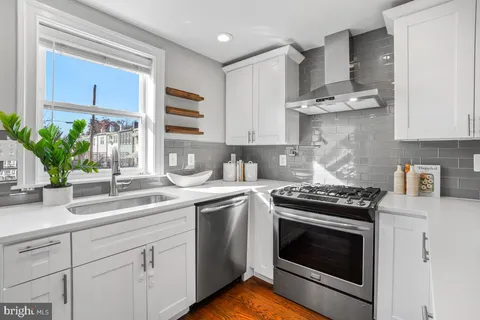 a kitchen with stainless steel appliances white cabinets and a stove top oven
