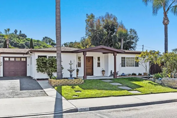 a front view of a house with a yard and potted plants