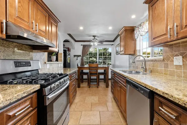 a kitchen with stainless steel appliances granite countertop a stove a sink and a microwave