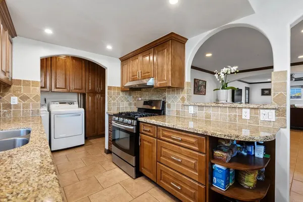 a kitchen with stainless steel appliances granite countertop a stove a sink and a refrigerator