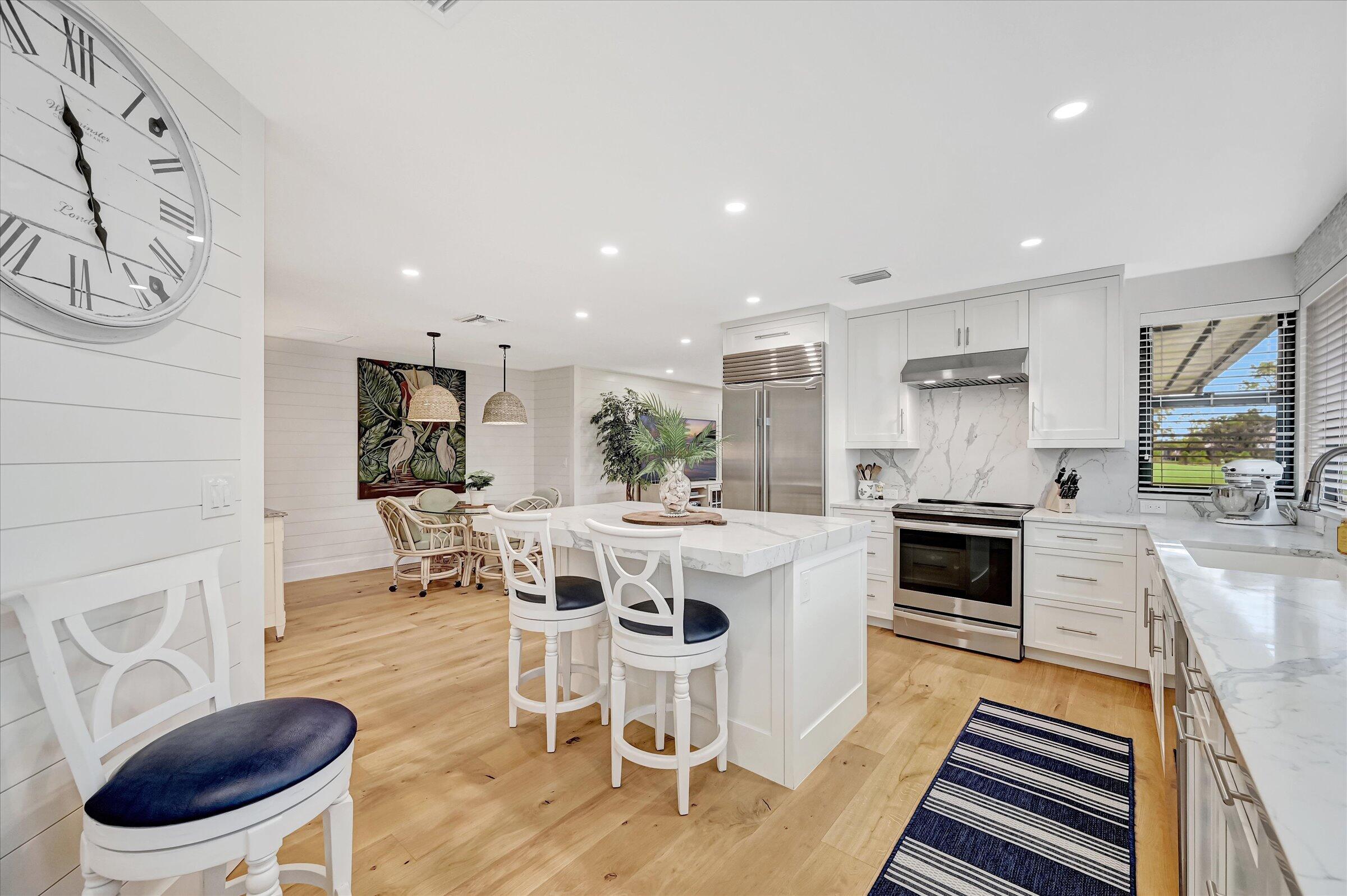 535 Augusta Boulevard, Unit 4 Naples, FL 34113 - Photo 20 of 44 a kitchen with stainless steel appliances kitchen island granite countertop a stove a sink a refrigerator and a dining table with wooden floor