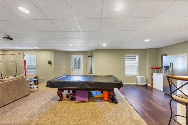 a living room with furniture pool table wooden floor and windows
