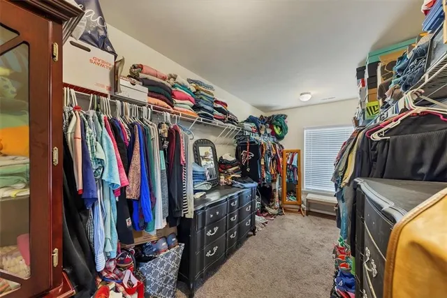 a view of walk in closet with clothes and shoes