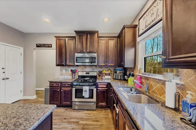 a kitchen with stainless steel appliances granite countertop a stove top oven a sink dishwasher and cabinets with wooden floor