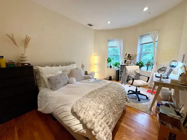 a large bedroom with bed and wooden floor