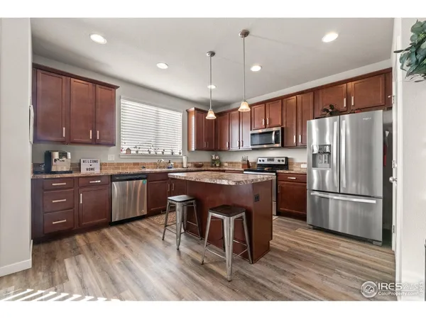 a kitchen with stainless steel appliances granite countertop a refrigerator a sink dishwasher a stove with wooden floors