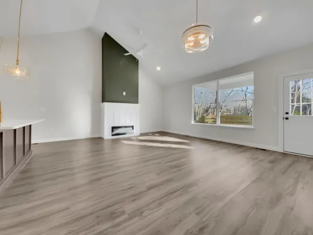 a view of an empty room with window and wooden floor