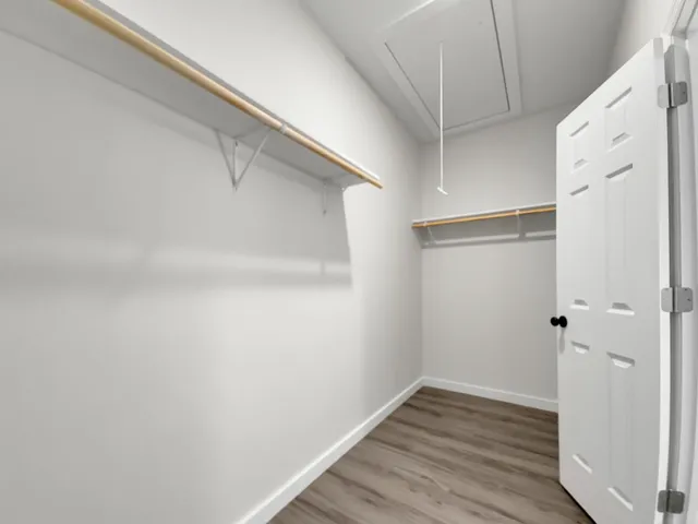 an empty room with wooden floor chandelier fan and windows