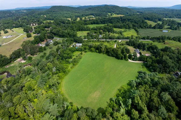 an aerial view of residential houses with outdoor space and trees all around