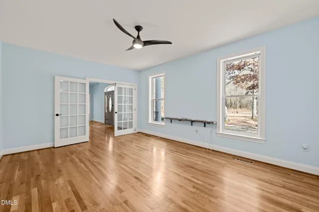 a view of an empty room with wooden floor and a window