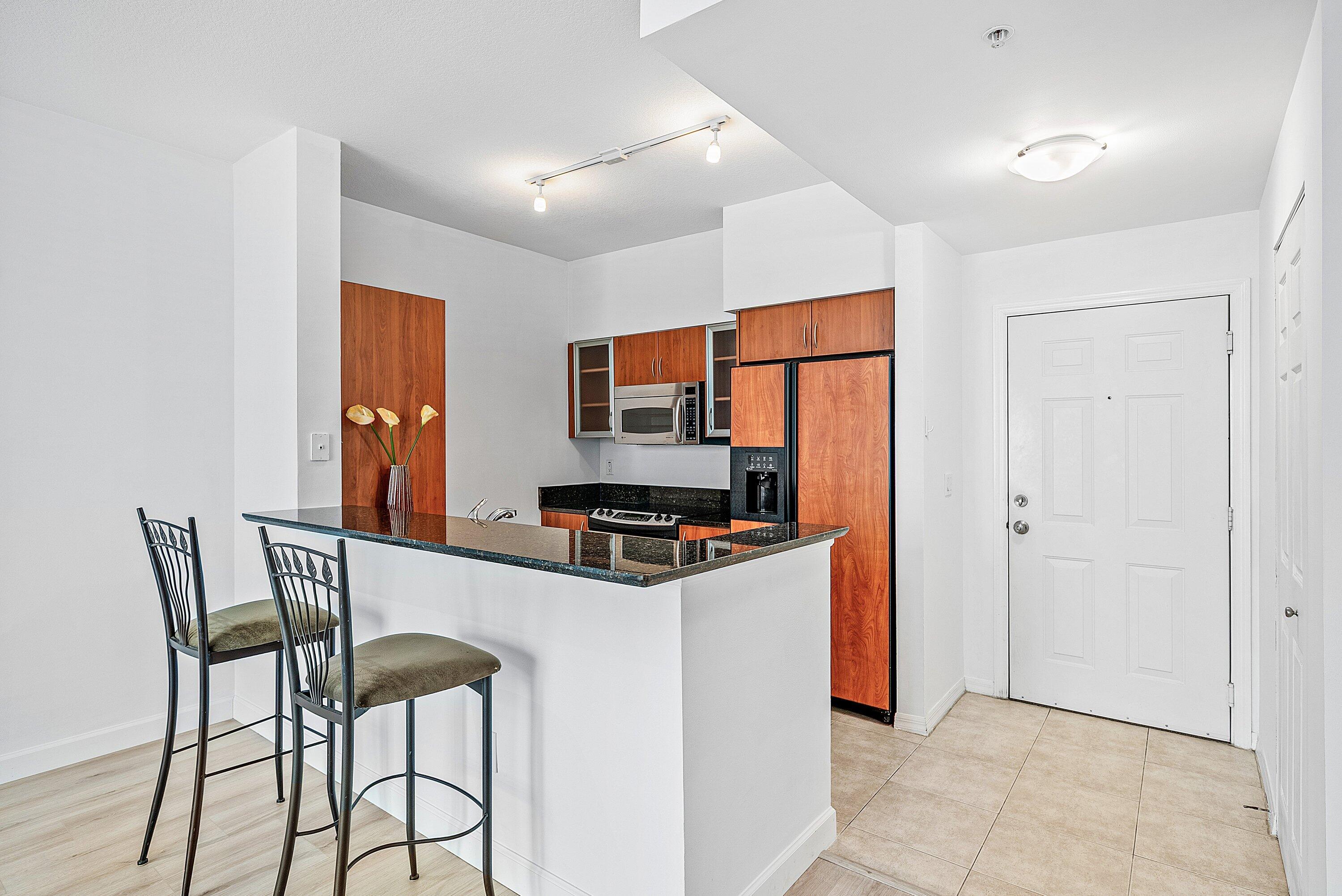 233 South Federal Highway, Unit 404 Boca Raton, FL 33432 - Photo 7 of 34 a kitchen with stainless steel appliances granite countertop a stove top oven a sink a dining table and chairs with wooden floor