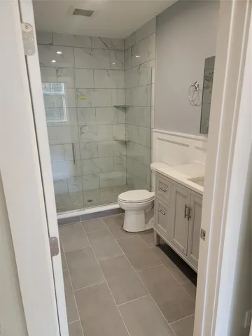 a bathroom with a toilet a sink a shower and mirror