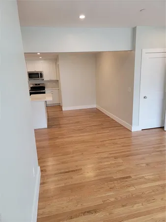 a view of kitchen and empty room with wooden floor