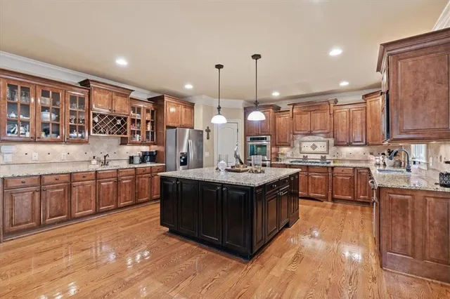 a kitchen with stainless steel appliances granite countertop a sink a stove and a wooden floors