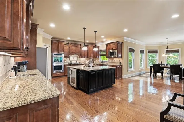 a kitchen with kitchen island granite countertop a stove a sink dishwasher and a wooden cabinets with wooden floor