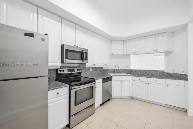 a kitchen with granite countertop white cabinets and white stainless steel appliances