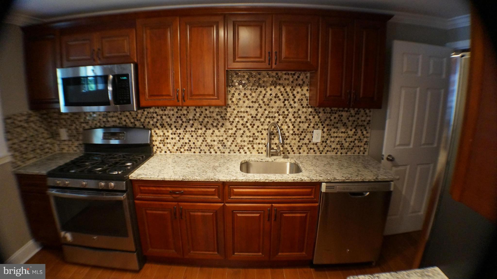 1233 Kevin Road Baltimore, MD 21229 - Photo 7 of 22 a kitchen with granite countertop wood cabinets and stainless steel appliances