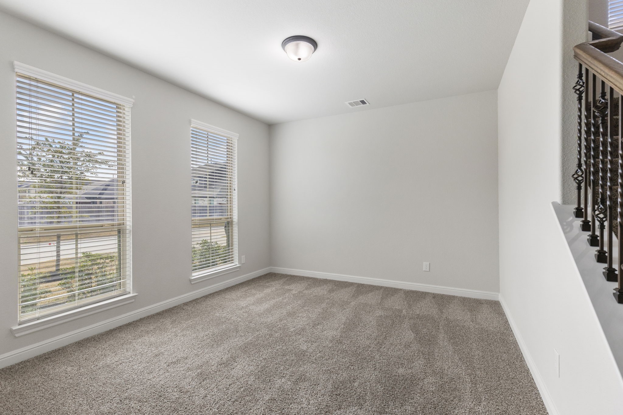 2819 Bradbury Hills Road Spring, TX 77373 - Photo 9 of 50 Discover a bright and inviting living/seating room featuring plush carpet, abundant natural light from large windows, and a stylish railing accent, perfect for relaxation and entertaining.