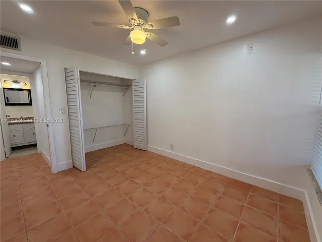 an empty room with closet and a chandelier fan