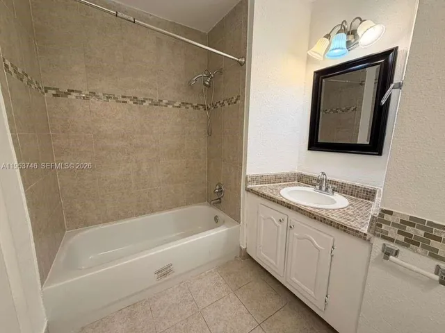 a bathroom with a granite countertop sink mirror vanity and bathtub