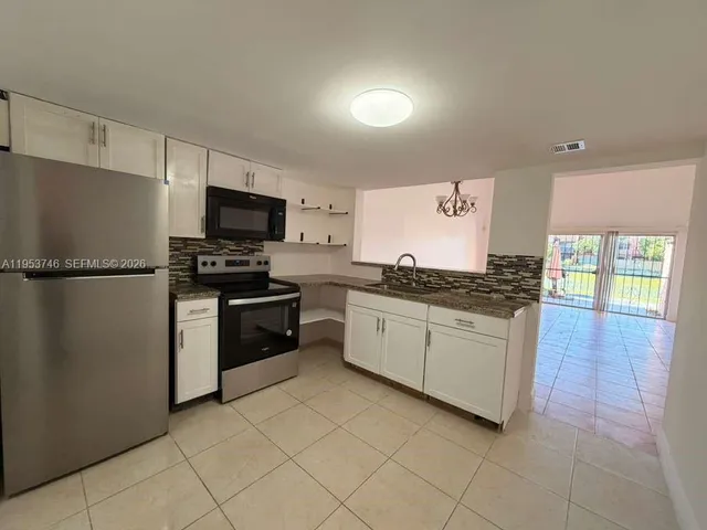 a kitchen with stainless steel appliances granite countertop a refrigerator and a stove top oven