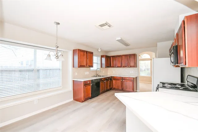 a kitchen with stainless steel appliances granite countertop a stove top oven a sink dishwasher and a refrigerator with wooden cabinets