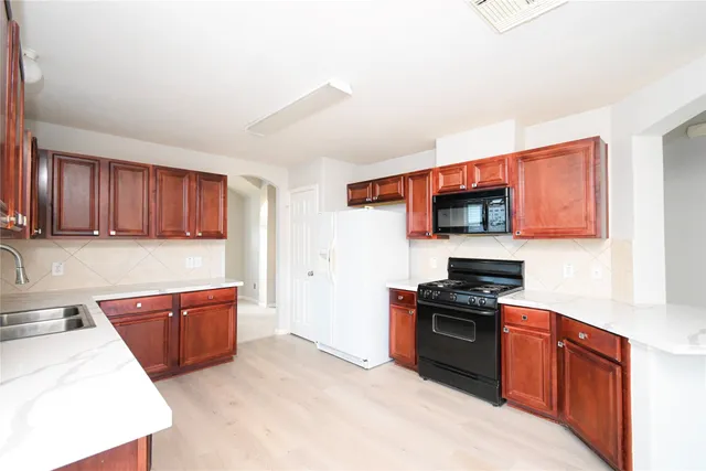 a kitchen with stainless steel appliances kitchen island granite countertop a sink dishwasher stove and cabinets with wooden floor